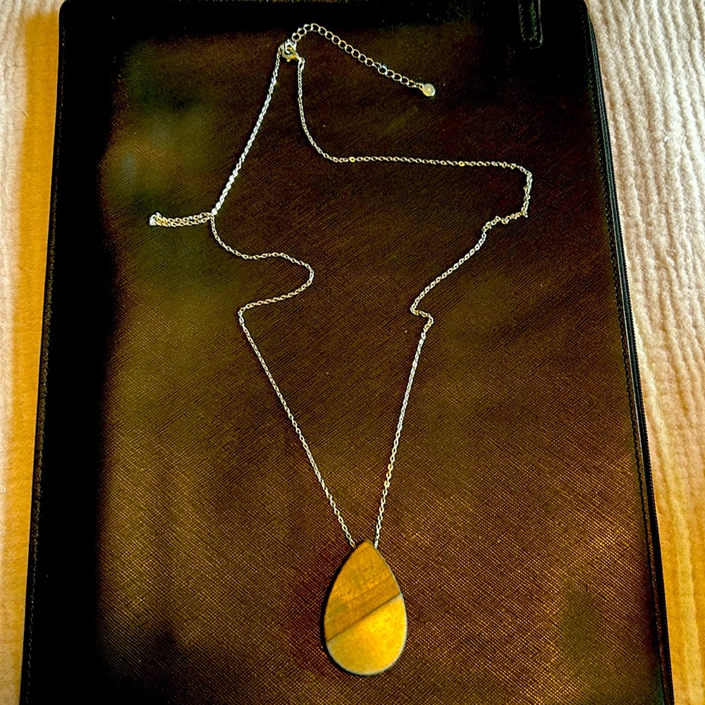 Maurice’s long silver necklace with wood tear shaped accent piece.